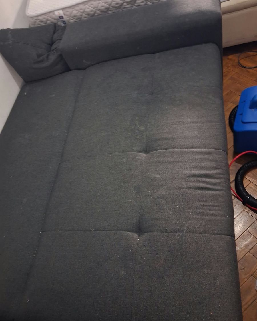 Sofá-cama cinzento-escuro com manchas claras no tecido