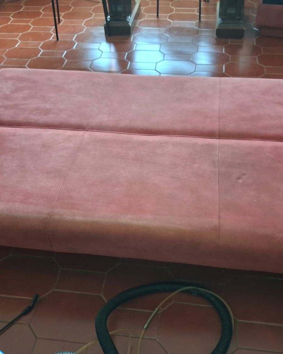 Sofá-cama vermelho aberto, com pó e marcas no tecido